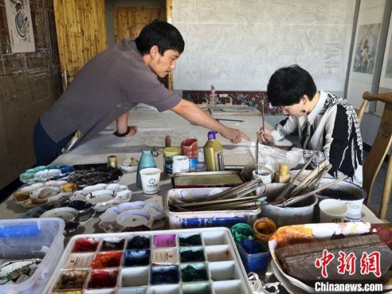 圖為2020年8月下旬，敦煌“80后”畫家張杰龍(左)在為云南麗江“學(xué)生”莫北講解敦煌壁畫的繪畫技巧。　馮志軍 攝