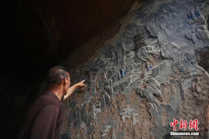 7月15日，甘肅省平?jīng)鍪袥艽h百里石窟長廊羅漢洞石窟內(nèi)，該窟文保員郭建平介紹窟內(nèi)石刻彩繪壁畫。郭建平家中三代人曾自發(fā)保護(hù)羅漢洞石窟。羅漢洞石窟遺存40余個窟龕，以北魏至清代風(fēng)格為主。中新社記者 李亞龍 攝