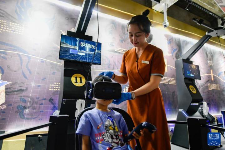 7月22日，敦煌研究院文化弘揚部工作人員引導游客佩戴使用VR設備。新華社記者 郎兵兵 攝</p>
<p>