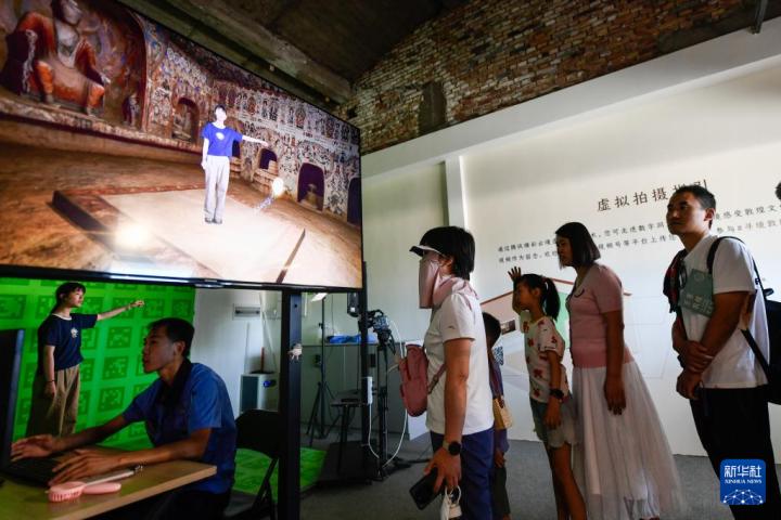 7月22日，游客體驗“尋境敦煌——數(shù)字敦煌沉浸展”后，在虛擬演播廳拍攝一段真人與洞窟虛擬場景交互的視頻。新華社記者 郎兵兵 攝</p>
<p>