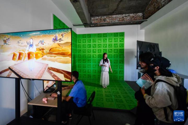7月22日，游客體驗“尋境敦煌——數(shù)字敦煌沉浸展”后，在虛擬演播廳拍攝一段真人與洞窟虛擬場景交互的視頻。新華社記者 郎兵兵 攝</p>
<p>